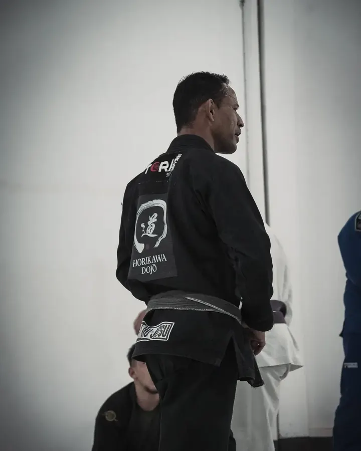 Aluno de kimono preto com o logo do Horikawa Dojo estampado nas costas